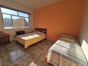 A bedroom with two beds, a dresser, and a window.