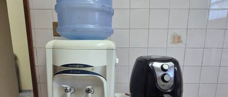 Un dispensador de agua y un tostador sobre una mesa con mantel.