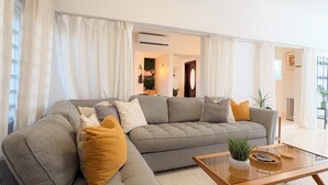 Uma sala de estar moderna com um sofá modular, uma mesa de centro de vidro e um ventilador de teto.