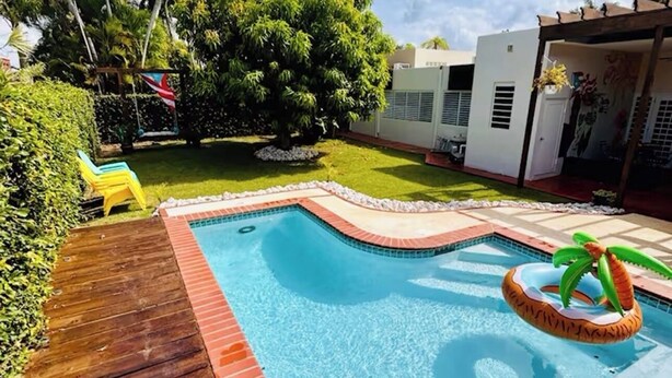 Piscina com deck de madeira e boia em formato de palmeira.