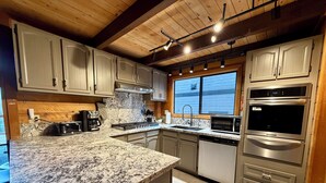 Una cocina moderna con encimeras de granito, electrodomésticos de acero inoxidable y armarios de madera.