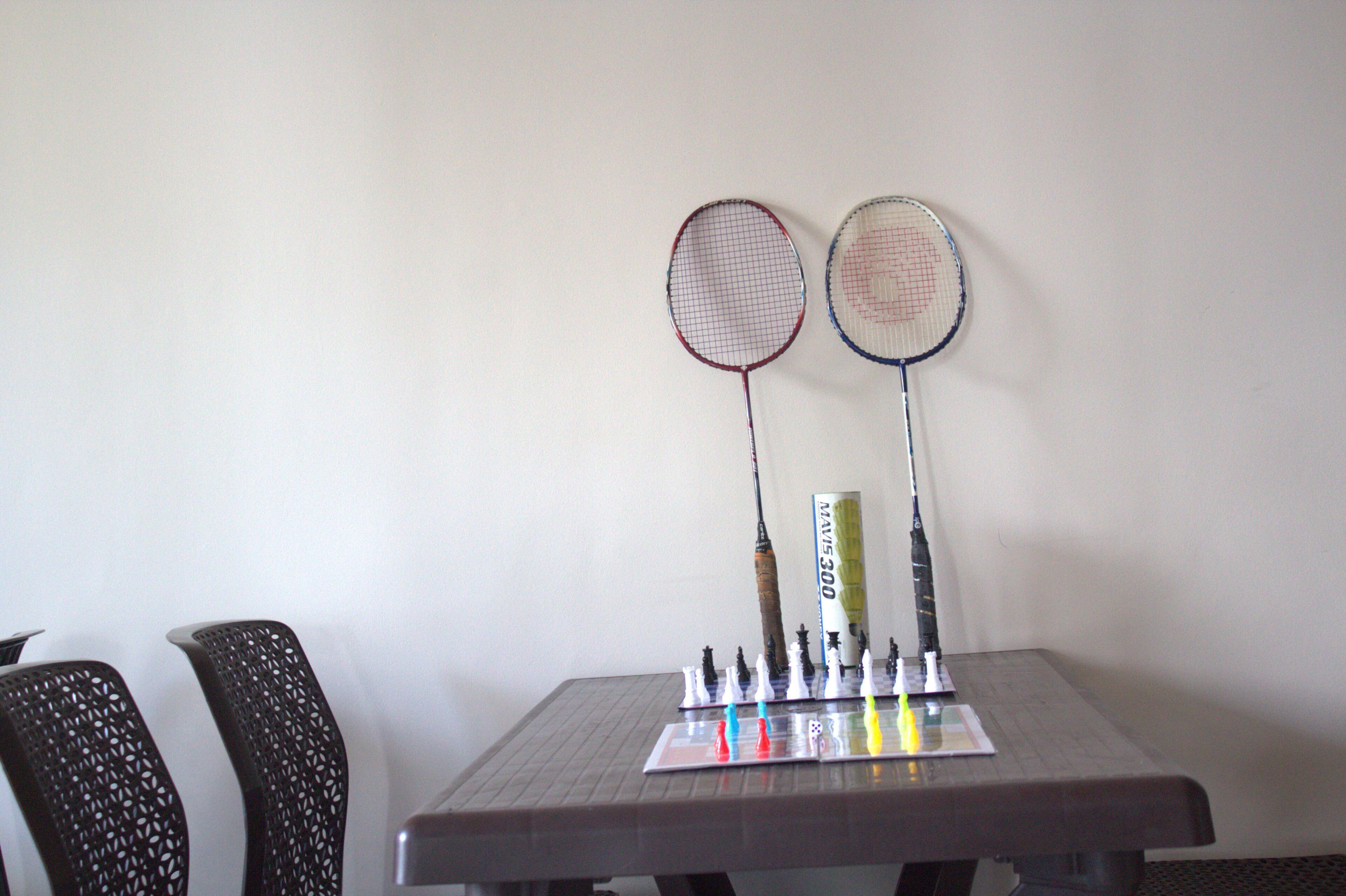 Una mesa con dos raquetas de bádminton, un trofeo y un tablero de ajedrez.