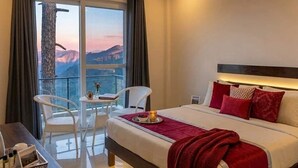 Ein Hotelzimmer mit Bett, kleinem Tisch mit Tablett, zwei Stühlen und einem Balkon mit Blick.