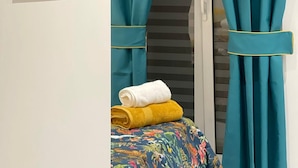 Een slaapkamer met teal gordijnen, een bed met bloemenbedekking en een ingelijst kunstwerk aan de muur.