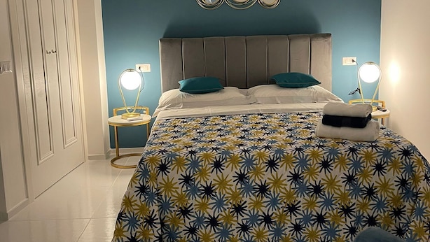 Een slaapkamer met een bed, nachtkastjes, een airconditioning en een spiegel aan de muur.