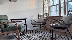 A room with a herringbone-patterned wooden floor, a blue and white patterned rug, and three wicker chairs with cushions. - Charming Vintage Home w/Separate Barn Guesthouse and Yard (San Antonio)