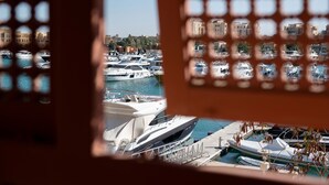 Vista a través de una ventana con diseño de cuadrícula de un puerto deportivo con varios yates amarrados.