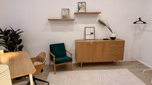 Ein modernes Wohnzimmer mit einem Holzschrank, einem grünen Sessel, einem kleinen Tisch und einer Stehlampe.