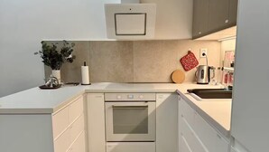 Eine moderne Küche mit weißen Schränken, einem eingebauten Backofen und einer Spüle aus Edelstahl.