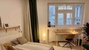 Ein gemütliches Schlafzimmer mit zwei Betten, einem Schreibtisch und einem Fenster mit Jalousien.