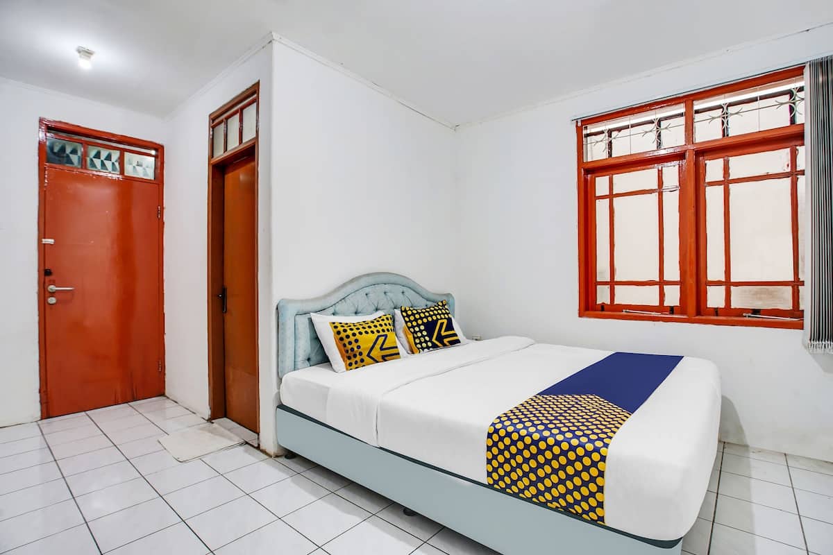 A room with a bed, a window with red frames, and a door with a geometric pattern.