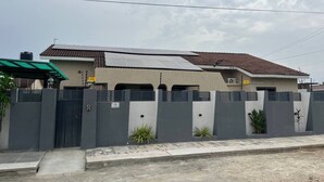 Una casa moderna de dos pisos con cerca gris, paneles solares y techo de tejas.