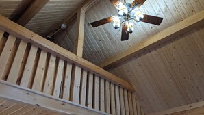 A wooden staircase with a ceiling fan and exposed beams.