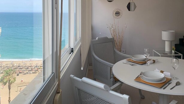 Een eethoek met uitzicht op de oceaan, een ronde tafel gedekt met borden en bestek, en twee hanglampen.