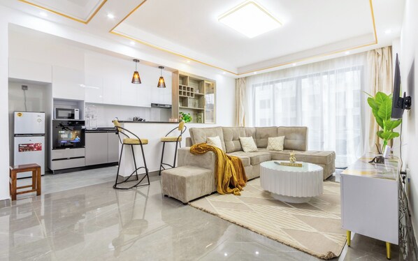 Una sala de estar moderna con un sofá, una mesa de centro y una cocina equipada.