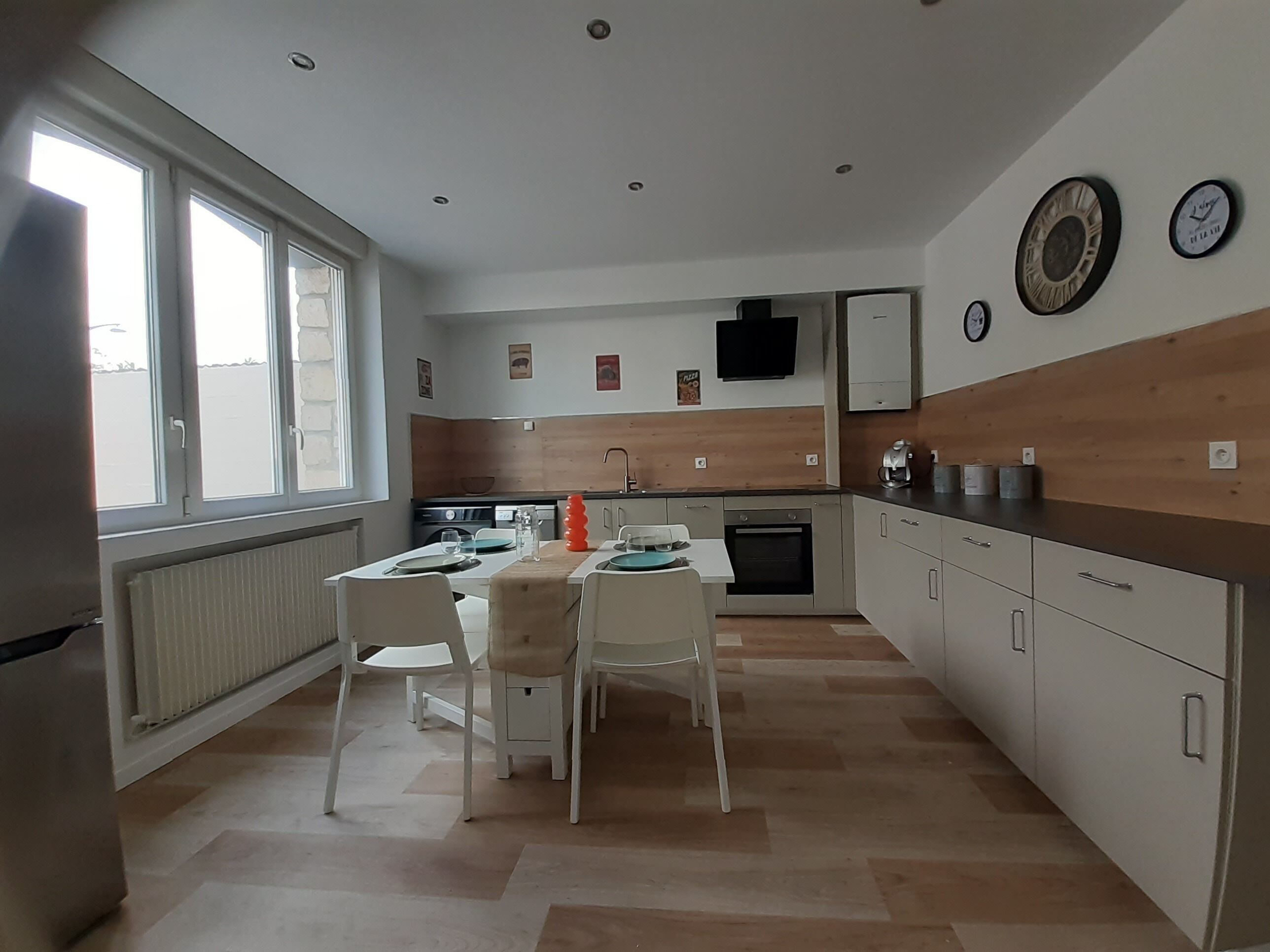 Une cuisine moderne avec un coin repas, des éléments décoratifs en bois et un four encastré.