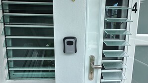 Una puerta blanca con un cartel de 'WELCOME', un adorno de pájaro y un timbre.