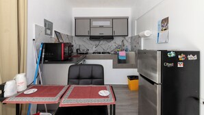 Una cocina compacta con armarios grises, un refrigerador negro y una zona de comedor con mantel rojo.