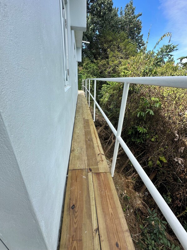 A wooden deck with a white railing leading to a building.