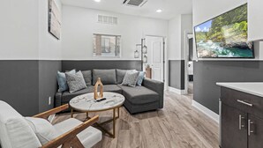 Ein modernes Wohnzimmer mit einem Ecksofa, einem runden Couchtisch und einem flachbildfernseher an der Wand.