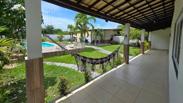 Un espacio al aire libre cubierto con piscina, una hamaca y vistas a una zona residencial.