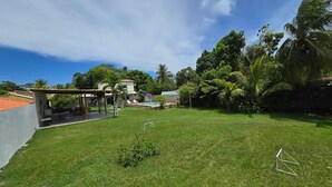 Un patio trasero con c ésped, una piscina, un gazebo y un pequeño jardín.