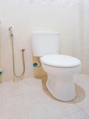 A bathroom with a toilet, a shower hose, and a blue water outlet. - OYO 91648 Losari Homestay (Makassar)
