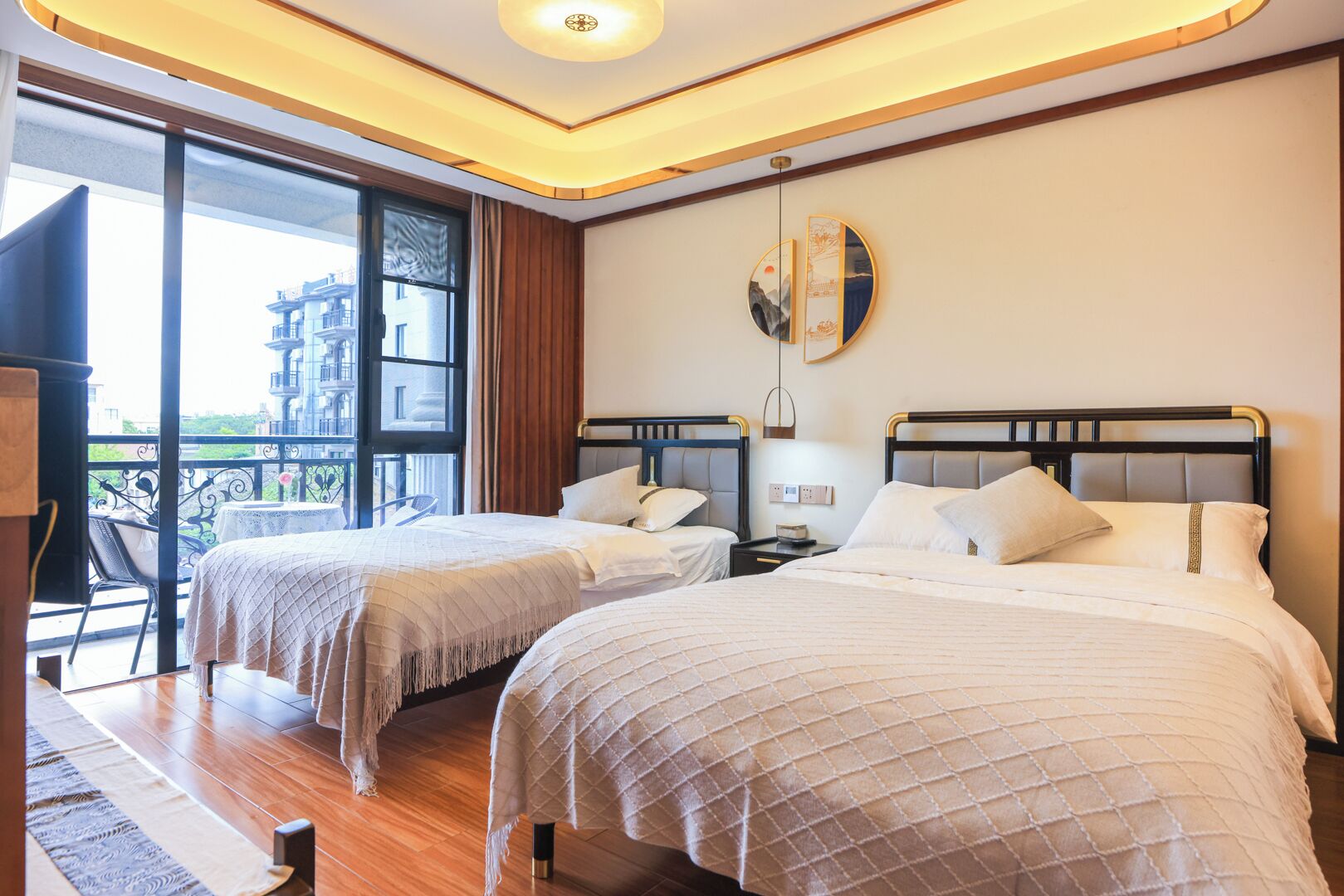 Habitación de hotel con dos camas, un balcón y vistas a un edificio.
