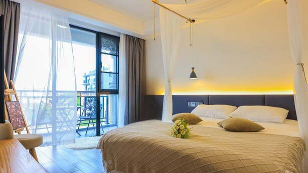 Ein Schlafzimmer mit einem großen Bett, einem Nachttisch, einem Sessel und einem Balkon mit Tisch und Stühlen.