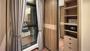 Et moderne soveværelse med et stort vindue, et garderobeskab med mange hylder og et natbord.