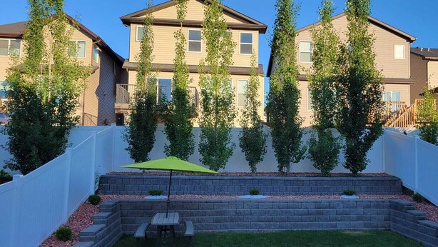 Un quartier résidentiel avec un petit patio, un parasol vert et un mur de briques.
