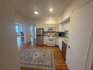 A kitchen with white cabinets, a stainless steel refrigerator, a stove, and a microwave.
