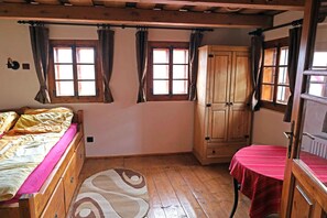 A wooden room with a bed, a table, and a cabinet.