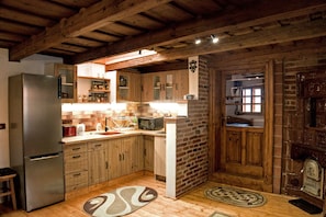 A kitchen with wooden cabinets, a refrigerator, a microwave, and a brick wall.