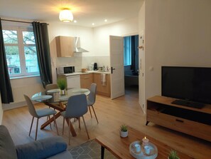 Un appartement moderne comprenant un coin repas, une cuisine, un salon et un téléviseur.