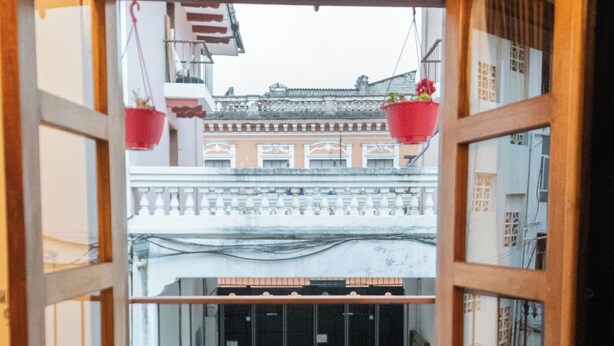 Una vista attraverso una porta aperta che dà su un balcone con piante in vaso e decorazioni appese.