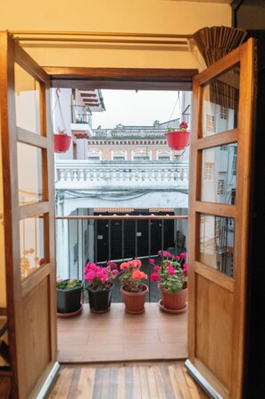 Uitzicht door een open deur naar een balkon met potplanten en decoraties.