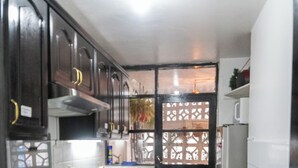 Una cucina compatta con mobili scuri, un fornello e un cestino per i rifiuti.