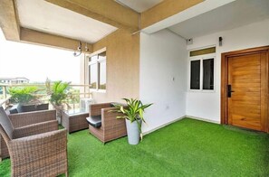 A balcony with wicker furniture, a potted plant, and a door.