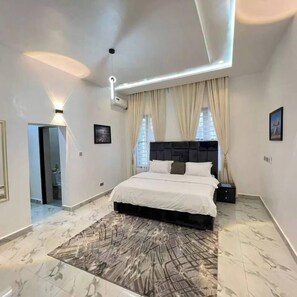 A modern bedroom with a large bed, a marble floor, and a ceiling light fixture.