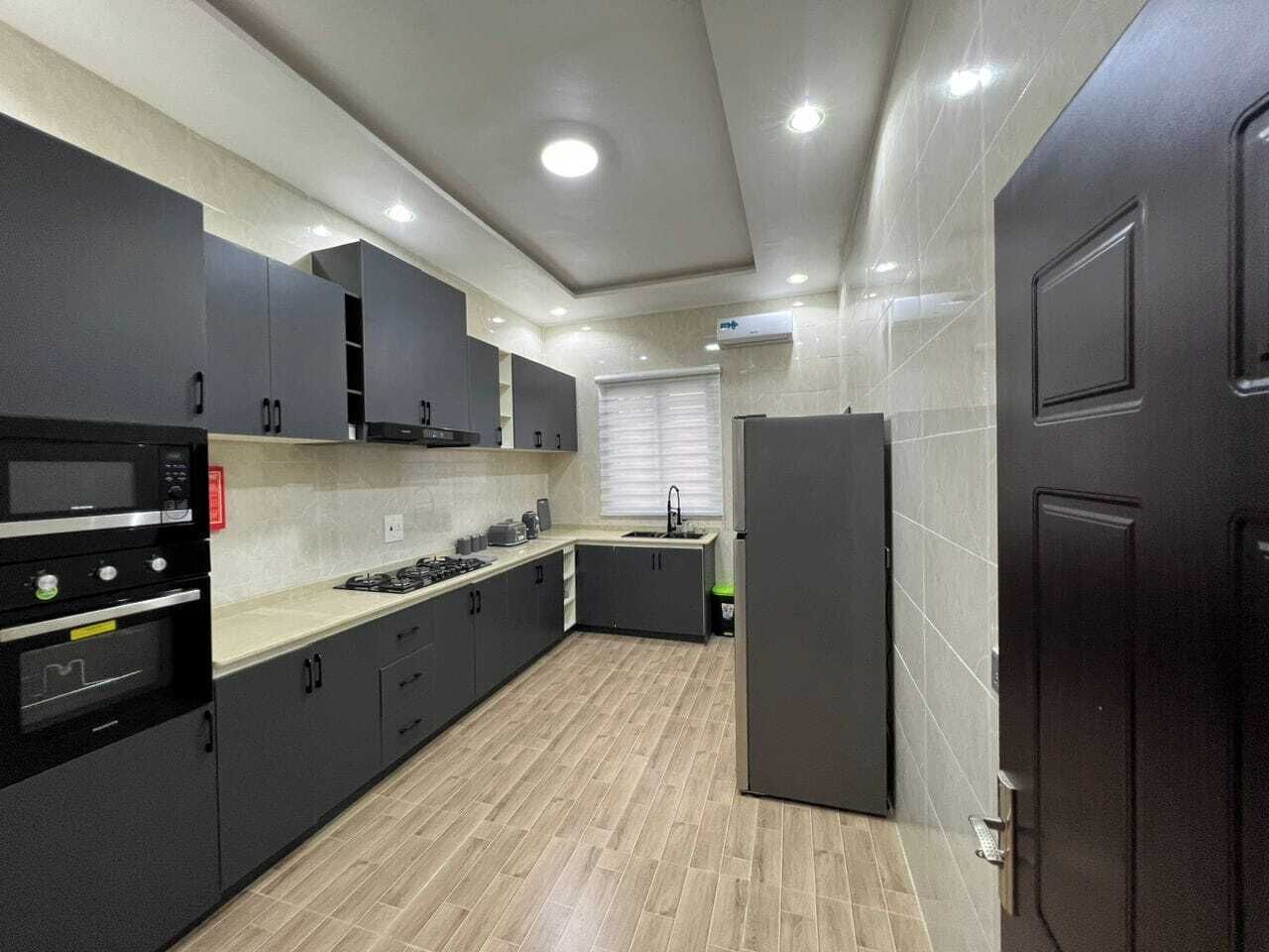 A modern kitchen with dark cabinetry, a built-in oven, and a refrigerator.