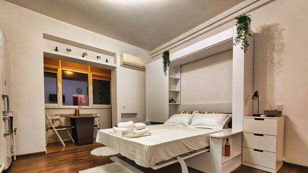 Quarto moderno com cama, mesas de cabeceira, escrivaninha e guarda-roupa.
