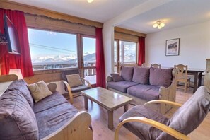A cozy living room with a sofa, chairs, a table, and large windows offering a mountain view. - 150m from ski slopes, 3rd floor, balcony, 53m², Méribel-Mottaret (Méribel - Les Allues)