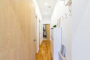 A narrow hallway with wooden flooring, white walls, and a white door on the left. - Stylish Two Bed Near London Bridge (London)