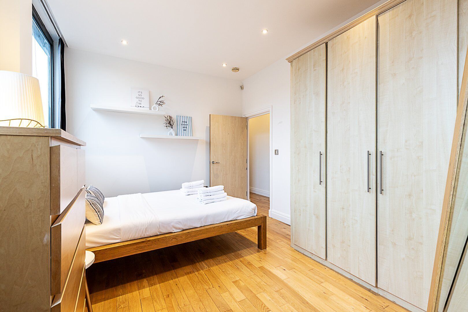 A bedroom with a wooden bed, a wardrobe, and a shelf with decorative items.