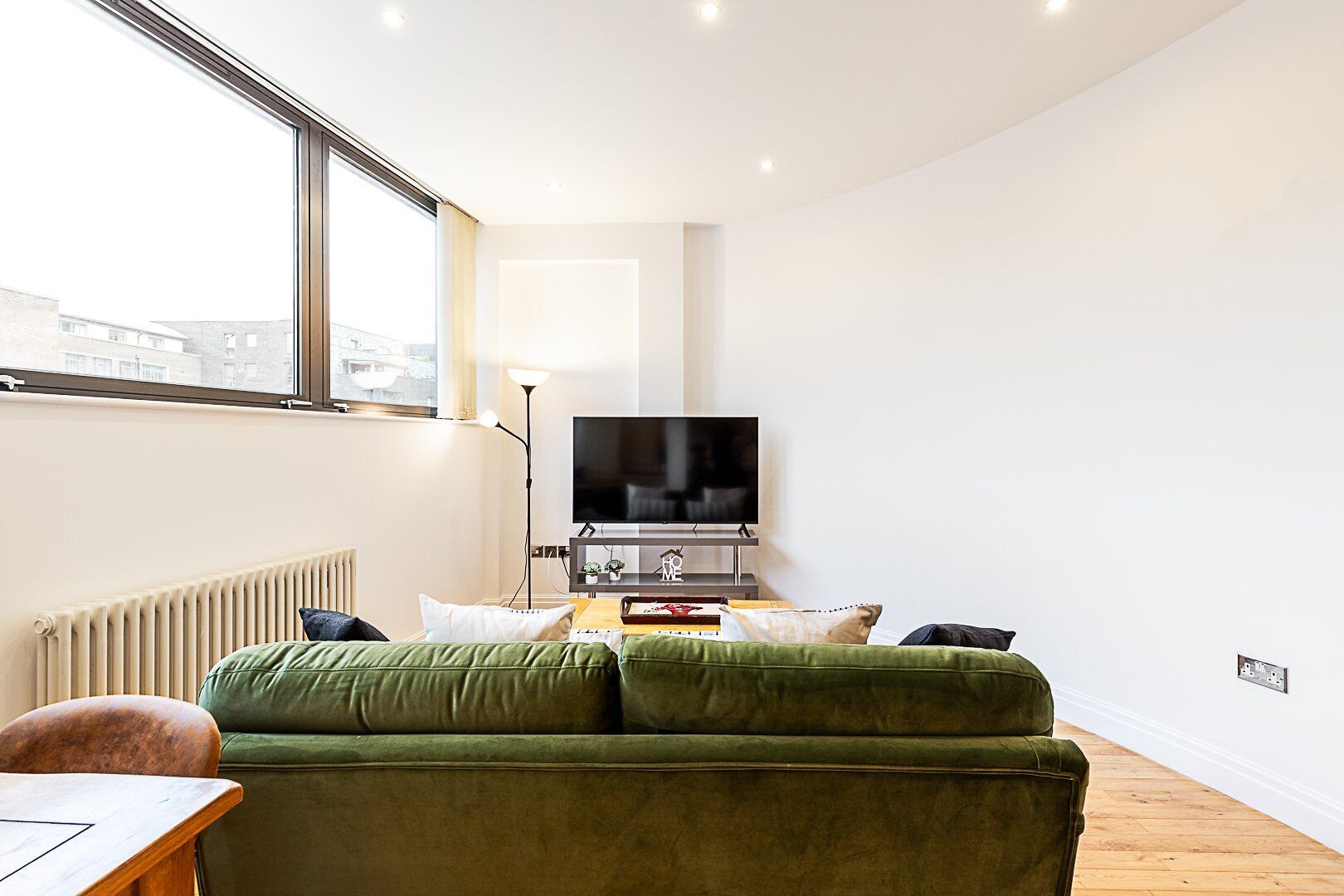 Una sala de estar moderna con un sofá verde, un televisor de pantalla plana y una mesa de centro de madera.