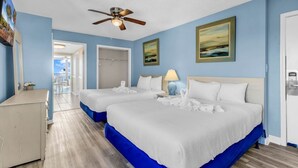 Una camera d'albergo con due letti, una ventola a soffitto e vista sull'oceano.