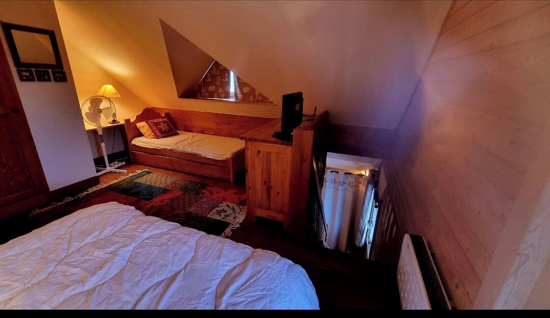 A bedroom with a bed, a wooden dresser, a lamp, and a radiator.