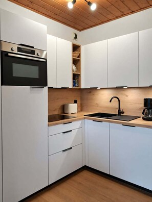 A modern kitchen with white cabinetry, a black oven, a built-in microwave, a toaster, a sink, and a coffee maker. - 150m from ski slopes, 3rd floor, tv, 95m², Peisey-Vallandry (Landry)