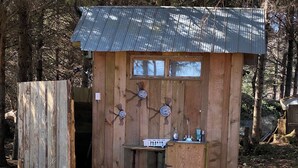 Une cabane en bois rustique, avec un toit en métal, une petite table et un banc.